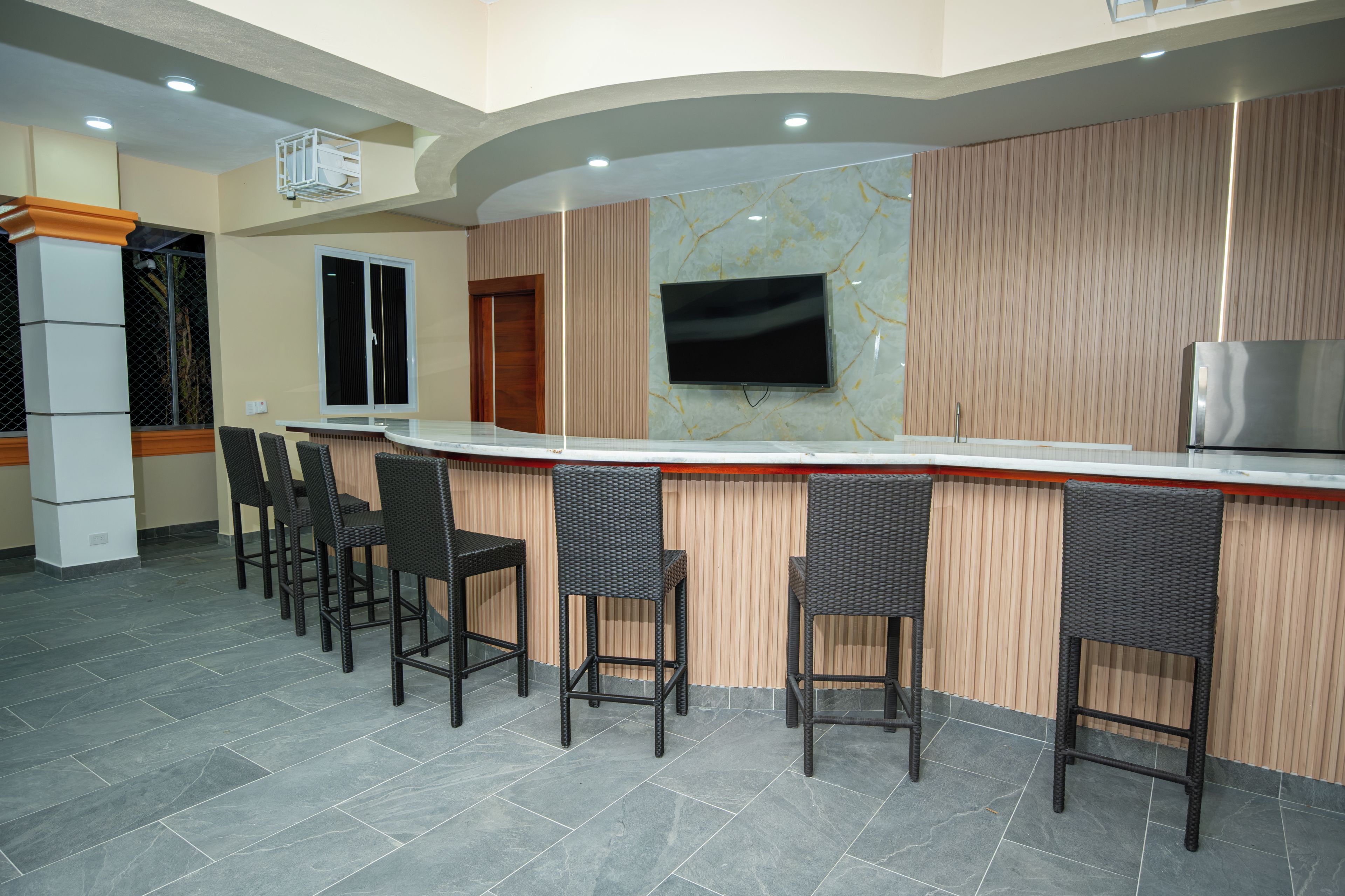 A bar area with a counter, seating, and a television.