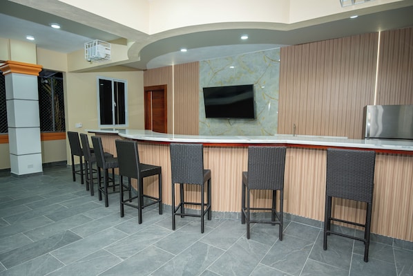 A bar area with a counter, seating, and a television.
