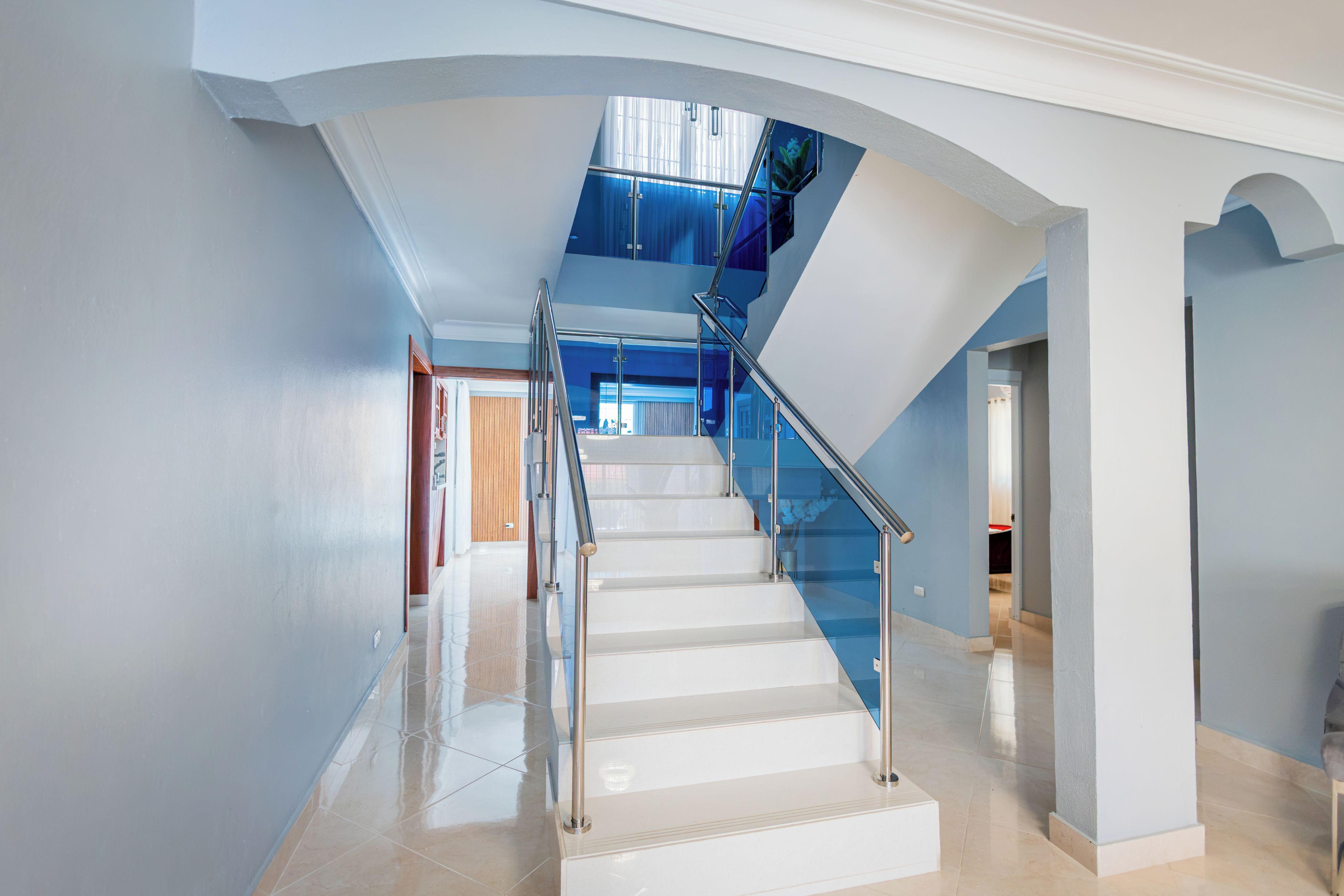 Ein modernes Interieur mit einer Glasstufen Treppe, die zu einer zweiten Etage führt.
