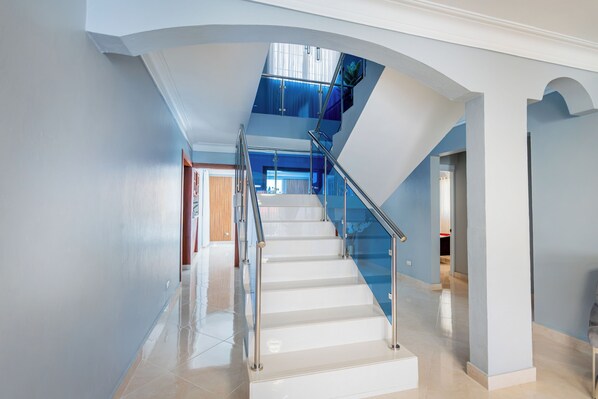 Un interior moderno con una escalera de cristal que conduce a un segundo piso.