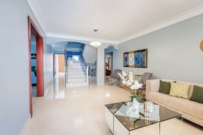 Un amplio salón con sofá, una mesa de centro y una escalera que lleva a un nivel superior.