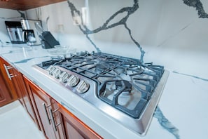 A kitchen with a stainless steel stove, wooden cabinets, and a marble backsplash. - Villa Mirella , Santiago Poolside retreat (Santiago de los Caballeros)