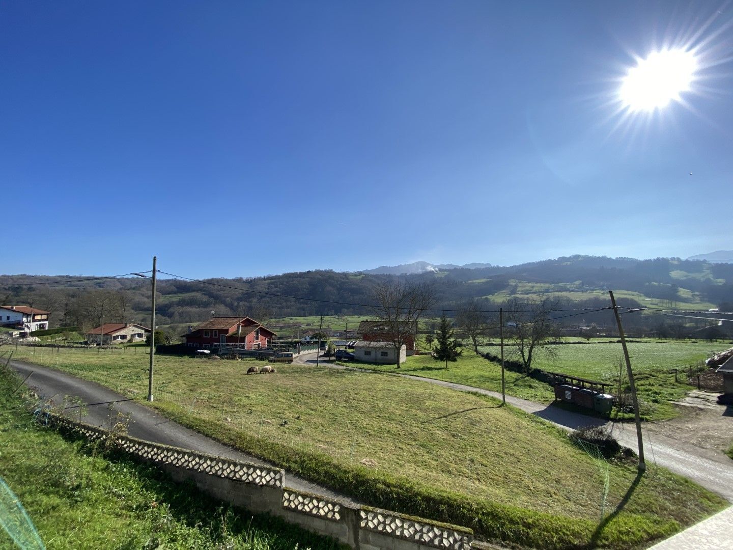Ländliche Landschaft mit Häusern, einer Straße und blauem Himmel.