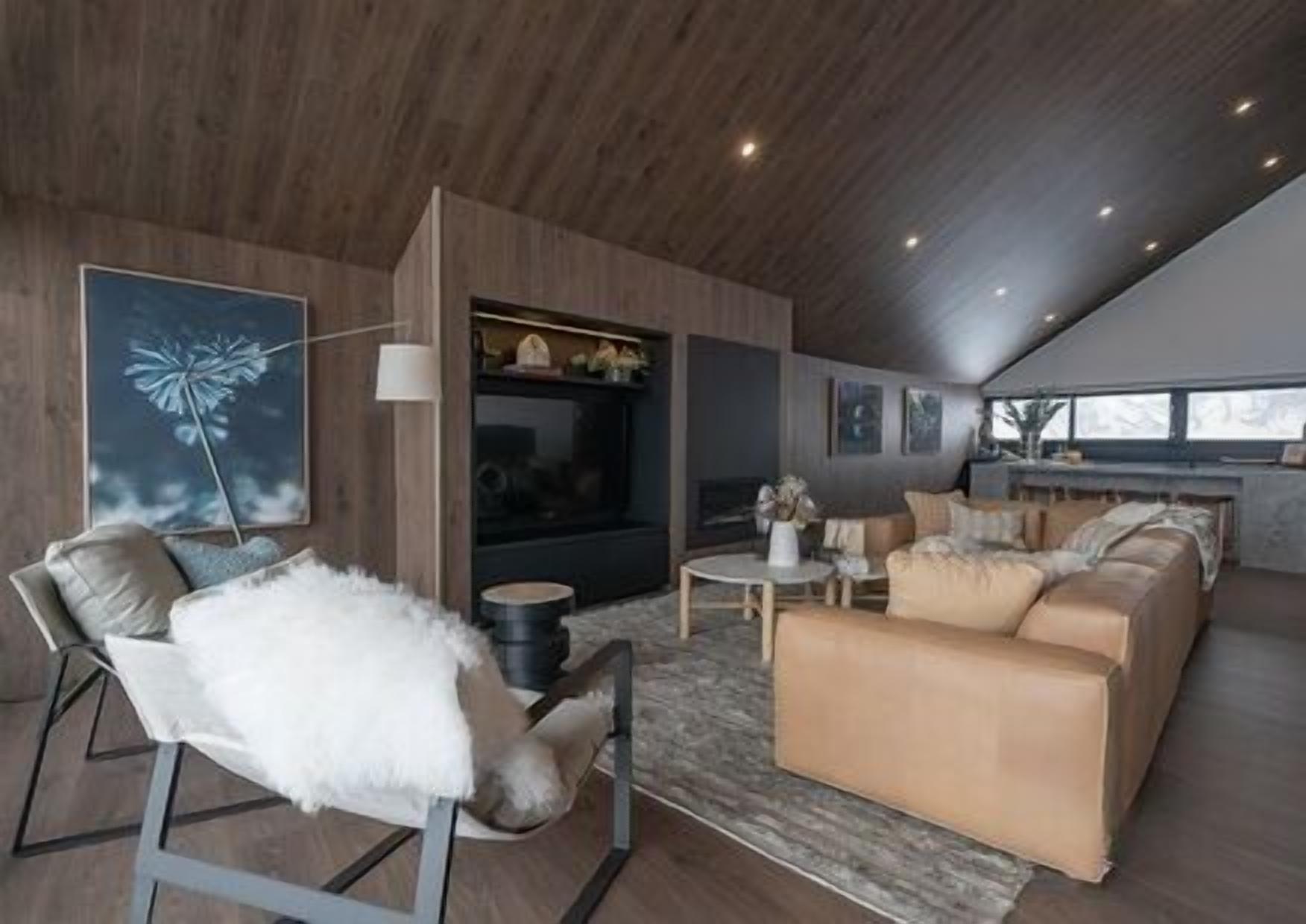 Un salon moderne avec une cheminée, un canapé, un fauteuil et une table basse.