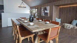 Un comedor moderno con una mesa de madera, sillas y una araña.