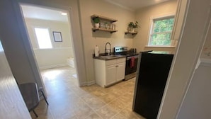 A kitchen with white cabinets, a black refrigerator, and a window with a view of greenery.