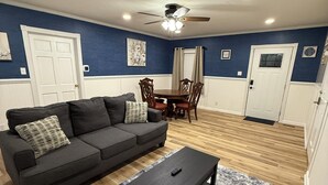 A living room with a dark gray sofa, a coffee table, and a dining table with chairs.