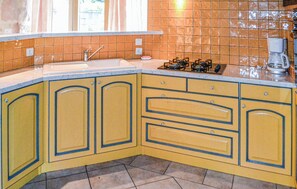 A kitchen with yellow cabinets, a gas stove, and a coffee maker.