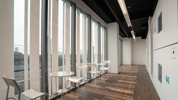 A modern interior with large windows, a long corridor, and a series of small tables and chairs. - Bobopod Kebayoran Baru Jakarta (Jakarta)