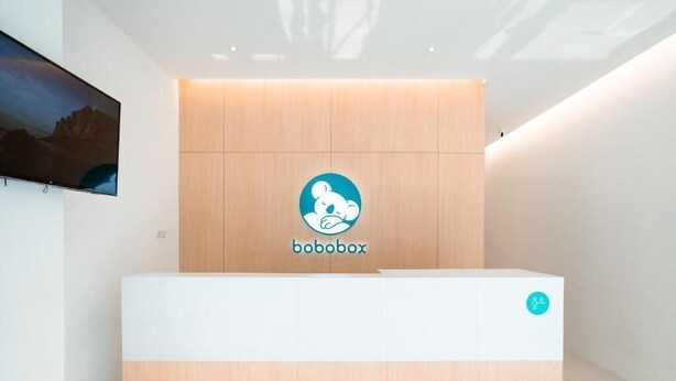 A reception desk with a wooden panel and a logo that reads "bobobox". - Bobopod Kebayoran Baru Jakarta (Jakarta)