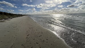 A beach with a clear sky and sunlight reflecting on the water.