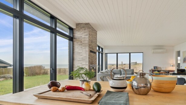 A modern kitchen with large windows, a wooden countertop, and a view of the outdoors.