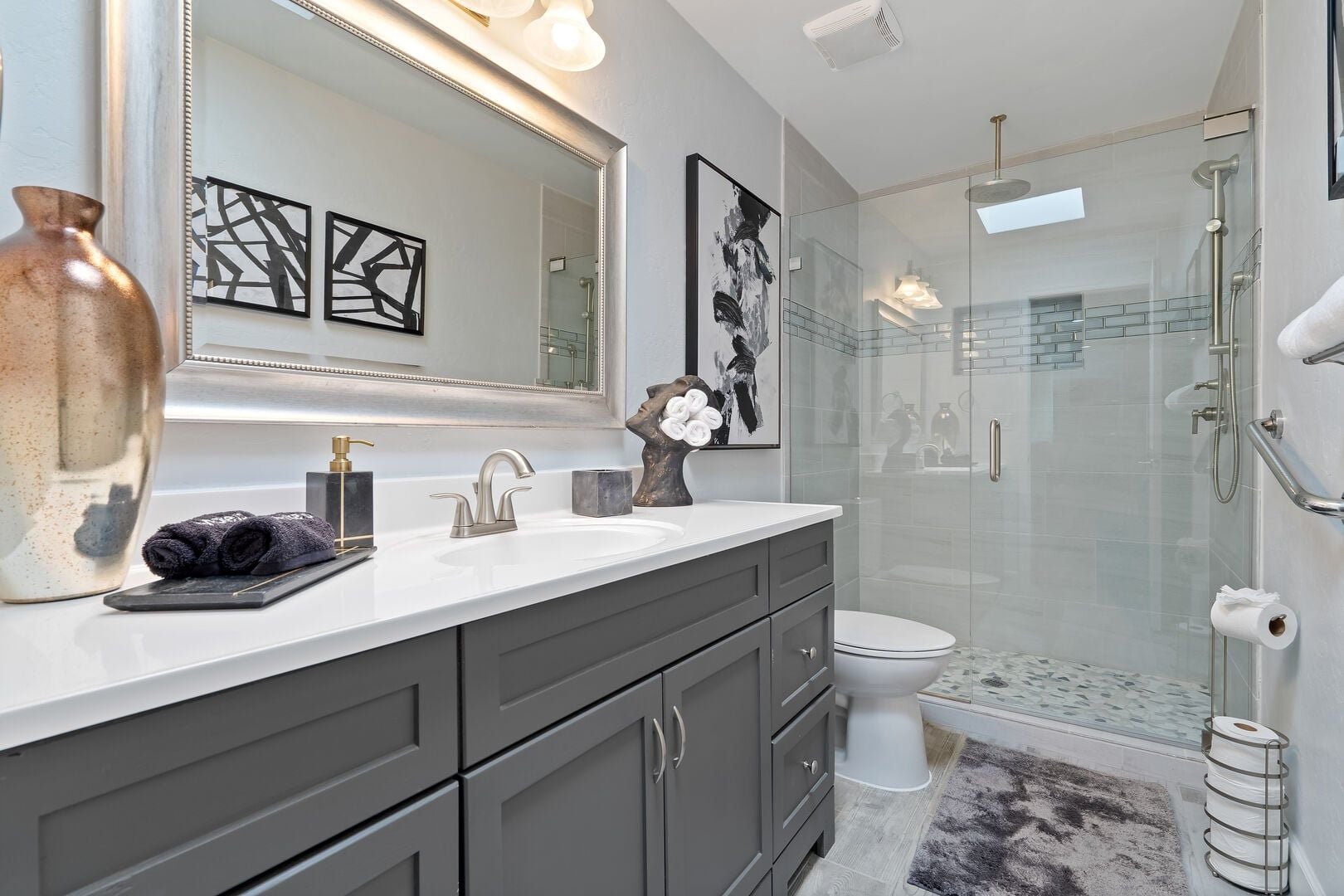 A modern bathroom with a glass shower enclosure, a white sink, and a large mirror.