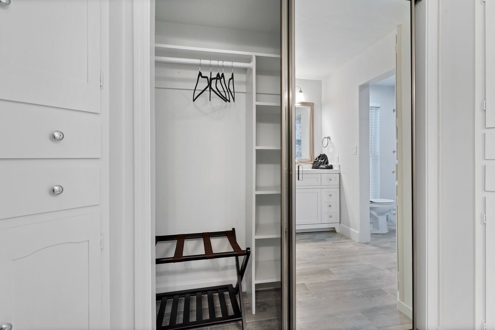 A walk-in closet with open shelving, a bench, and a hanging rack.