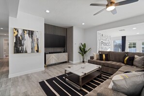 A modern living room with a flat-screen TV, a sofa, a coffee table, and a striped rug. - 5Bed • 5Bath Foothills Retreat • Pool • Guesthouse (Tucson)