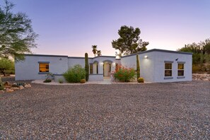 Une maison moderne à deux étages, avec une allée en gravier, un aménagement paysager minimaliste et un ciel dégagé.