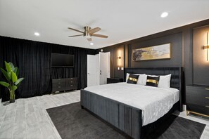 A modern bedroom with a large bed, a ceiling fan, a flat-screen TV, and a dark-colored wardrobe. - 5Bed • 5Bath Foothills Retreat • Pool • Guesthouse (Tucson)