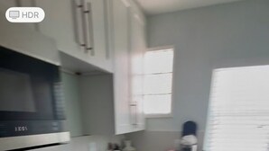 Una cocina moderna con armarios blancos, un lavamanos doble y un horno empotrado.