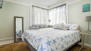 Un dormitorio con cama, espejo, mesita de noche y lámpara.