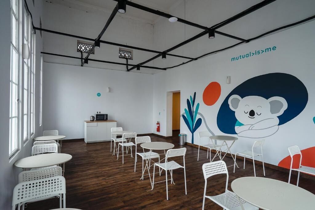 Una habitación moderna y luminosa con muebles blancos, un ventanal grande y un mural en la pared.