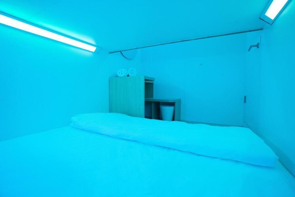 Quarto com uma cama, um pequeno armário de madeira e uma mesa de cabeceira.