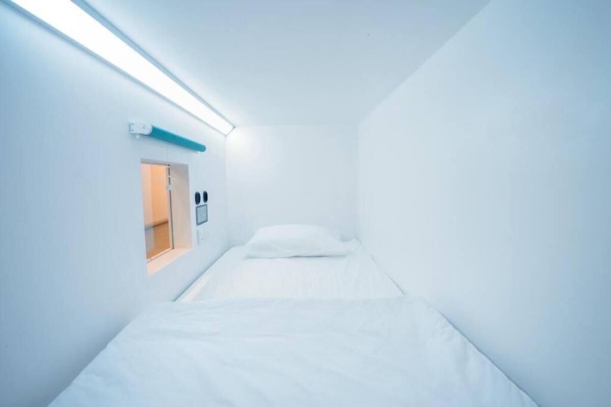 A small, narrow hotel room with a single bed and a window.