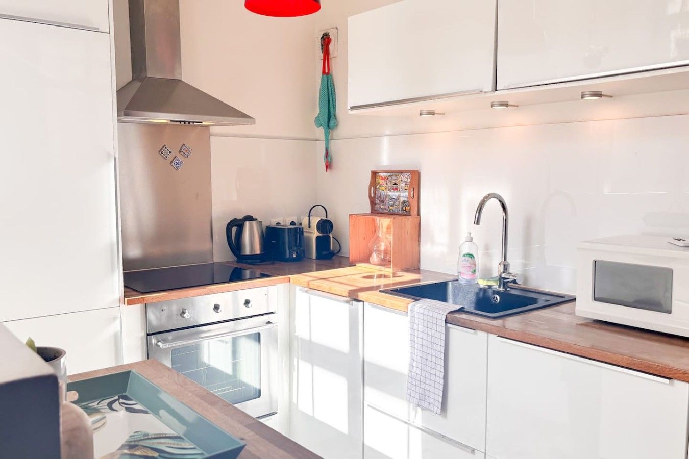 Een moderne keuken met witte kastjes, roestvrijstalen apparatuur, een houten aanrechtblad en een inbouwoven.
