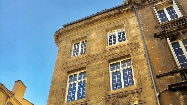 En byggnad med flera våningar, stora fönster och dekorativa järndetaljer.