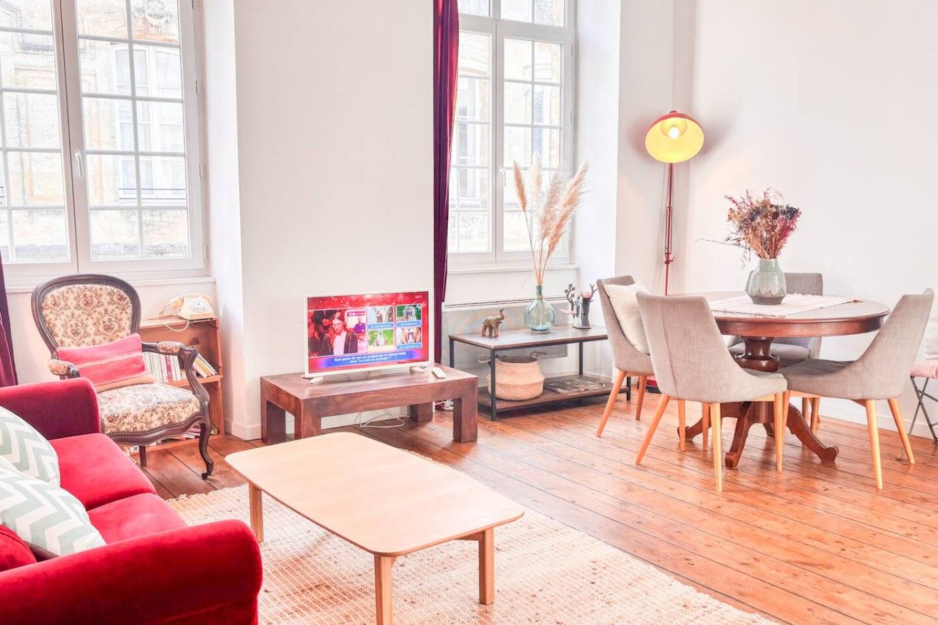 Un salon avec un téléviseur, une table à manger et un canapé rouge.