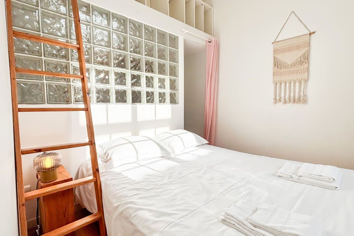 Une chambre avec un lit superposé, une échelle, une lampe de chevet, une décoration murale et une fenêtre avec des rideaux.