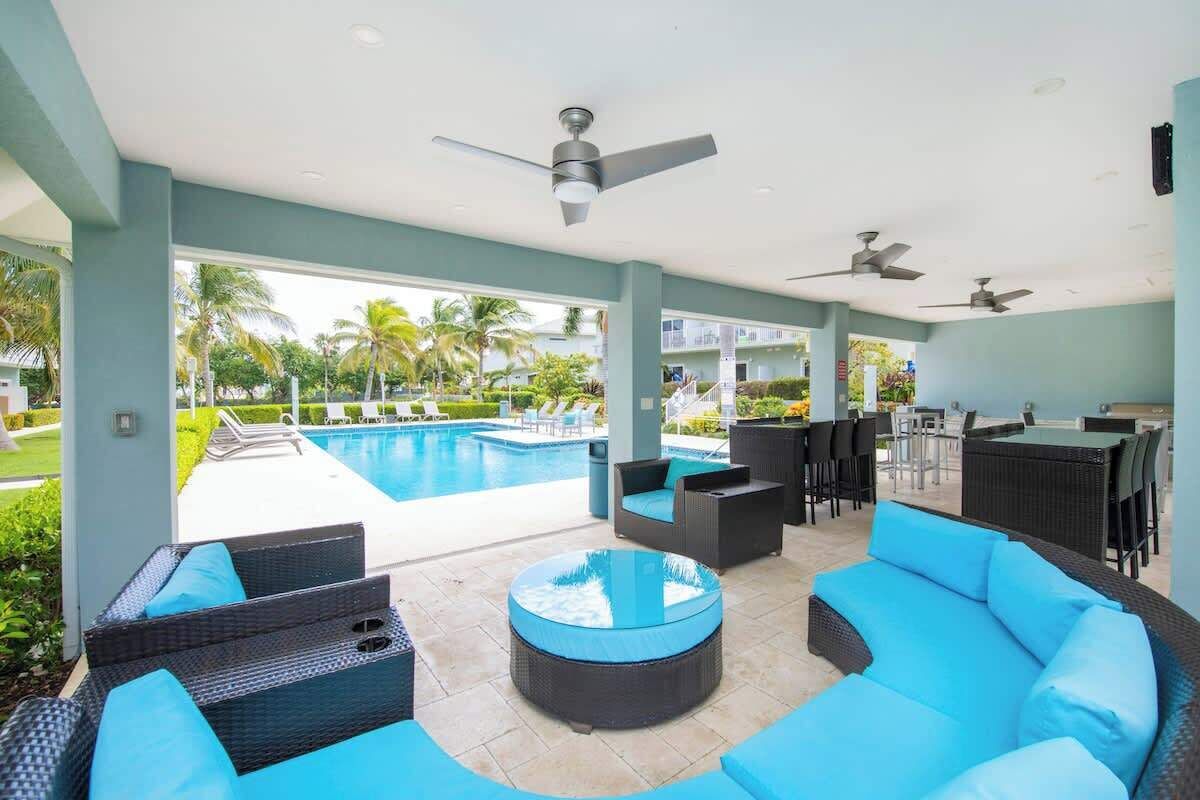 Un espace aménagé au bord de la piscine, avec des sièges extérieurs, un bar et une vue sur la piscine et la végétation.