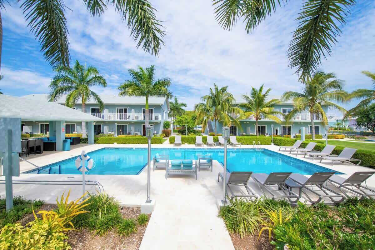 Un espace piscine avec des chaises longues et des palmiers.