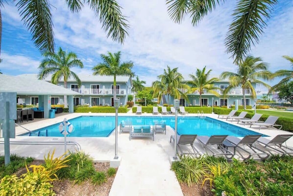 A pool area with lounge chairs and palm trees.