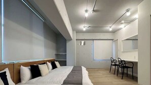 Et moderne hotelværelse med en stor seng, et skrivebord og stole.