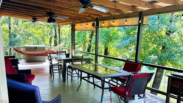 An outdoor patio with wooden flooring, seating, and a pergola structure.