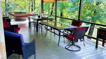 Une terrasse extérieure dotée d’un plancher en bois, de sièges et d’une structure en forme de pergola.