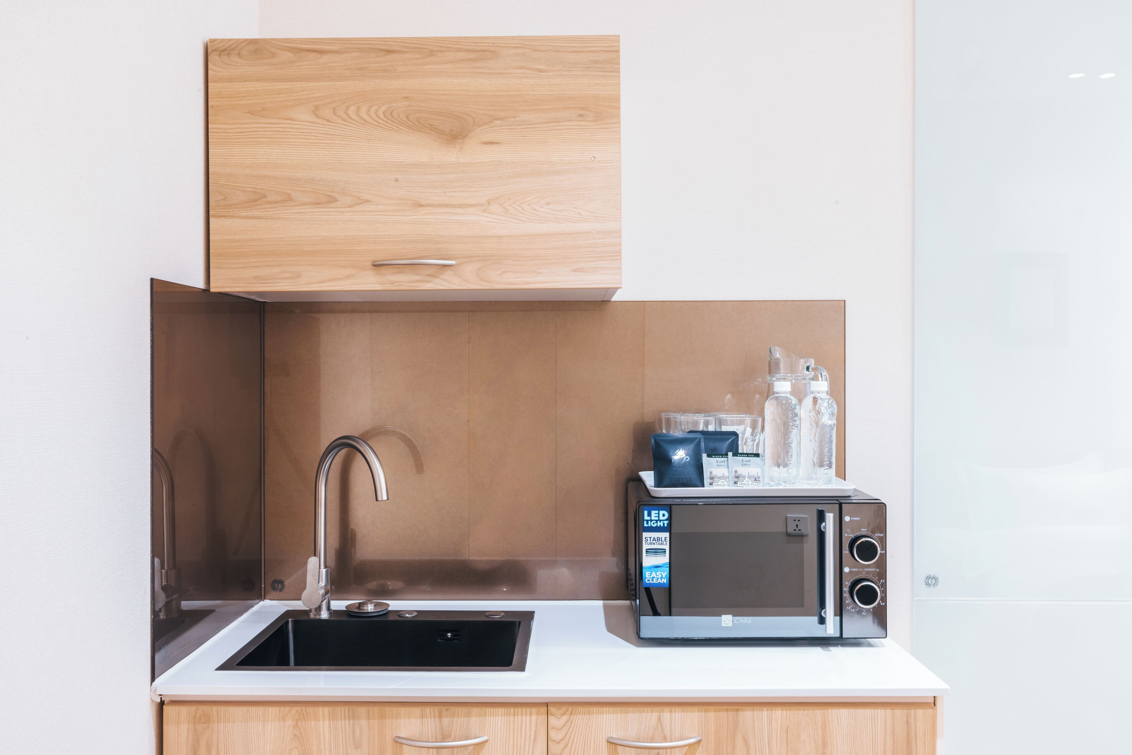 A modern kitchen with a built-in microwave, a sink, and wooden cabinetry.