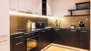 A modern kitchen with dark wood cabinets, a built-in oven, a microwave, and a coffee maker on the countertop. - May Seven Hotel and Suites (Ulaanbaatar)
