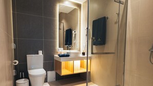 A modern bathroom with a glass shower enclosure, a toilet, a sink with a mirror, and a towel hanging on the wall. - May Seven Hotel and Suites (Ulaanbaatar)