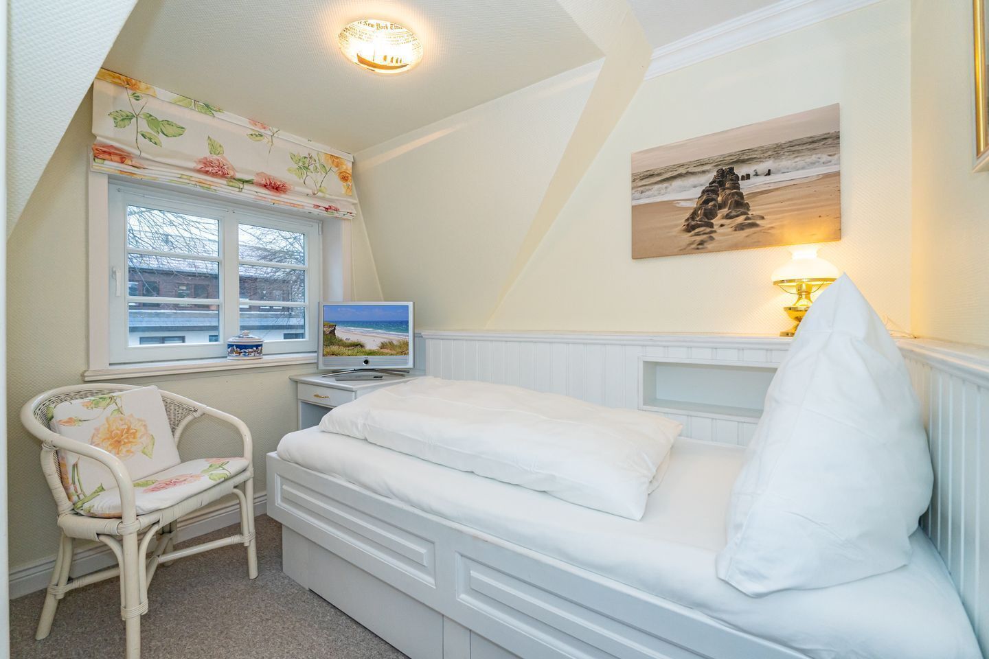 Une chambre à coucher avec un lit, une chaise, un téléviseur et un tableau accroché au mur.
