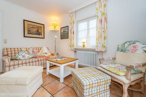 A cozy living room with a plaid sofa, a wooden coffee table, a patterned armchair, and a matching ottoman. - Kajüte - Friesische 2-zimmerwohnung mit Terrasse (Sylt)