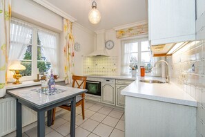 A kitchen with a dining table, oven, and sink. - Kajüte - Friesische 2-zimmerwohnung mit Terrasse (Sylt)
