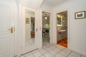 Un couloir avec des portes blanches donnant sur une cuisine et une salle de bain.