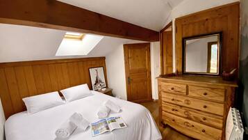 Une chambre à coucher avec un lit, une commode, une lucarne, une porte et une affiche accrochée au mur.