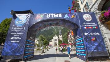 Un arco decorado con múltiples banderines y logotipos, incluyendo 'UTMB Mont-Blanc' y 'Columbia'.