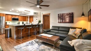 A modern kitchen with a central island, bar stools, and a dining area.