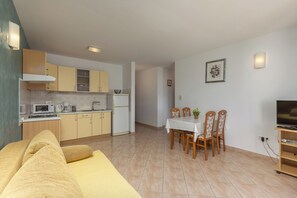 A compact living space with a kitchenette, dining area, and a TV stand.