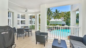 A balcony with a view of a swimming pool, outdoor furniture, and a grill. - 1 Bedroom Apartment Beach Club Palm Cove (Palm Cove)