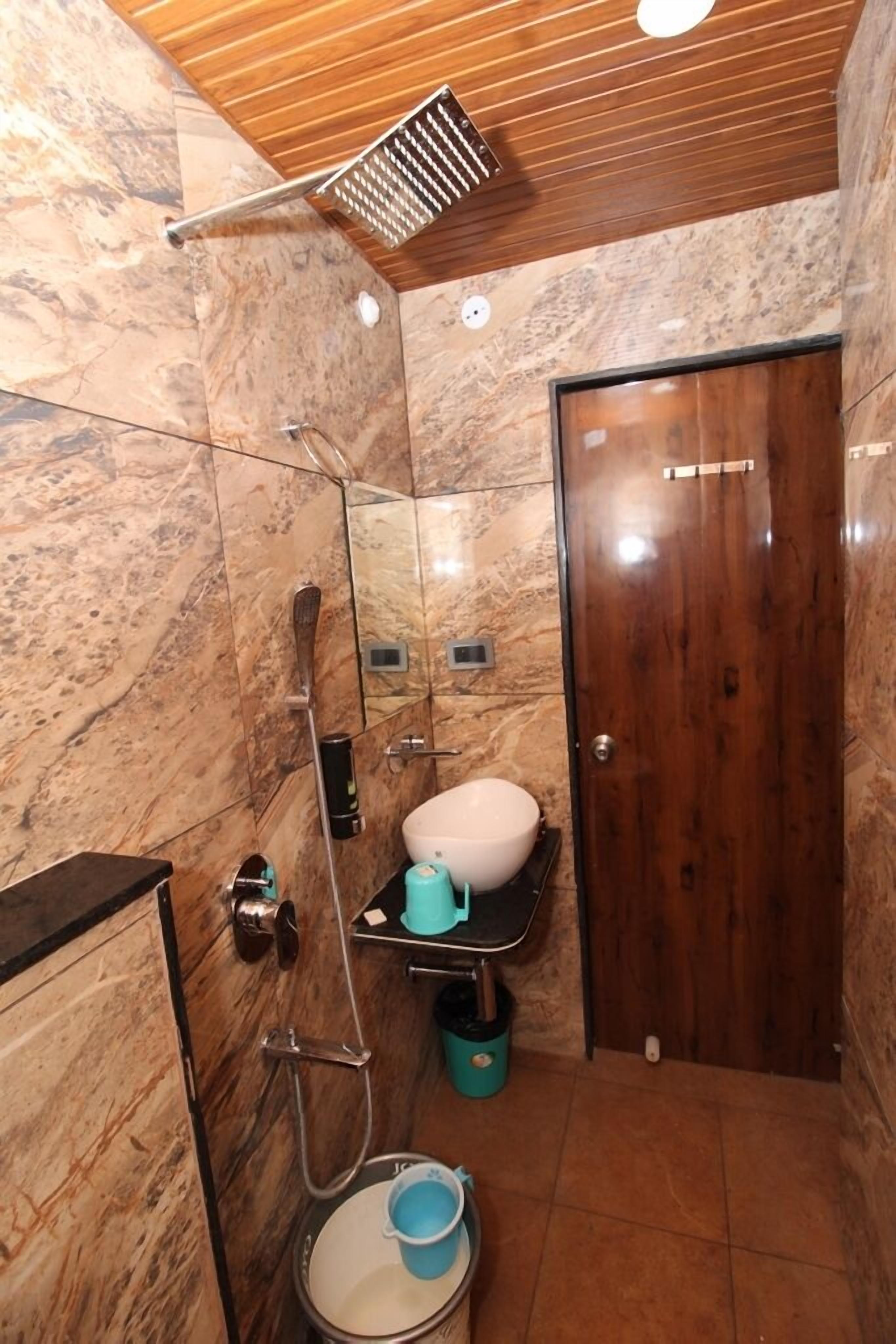 A bathroom with a marble floor, a wooden door, and a towel rack.