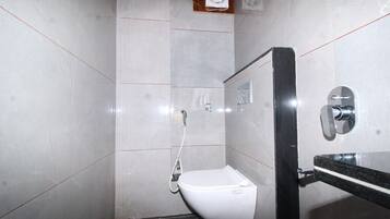 Une petite salle de bain moderne avec des toilettes blanches, une douche et un lavabo noir.